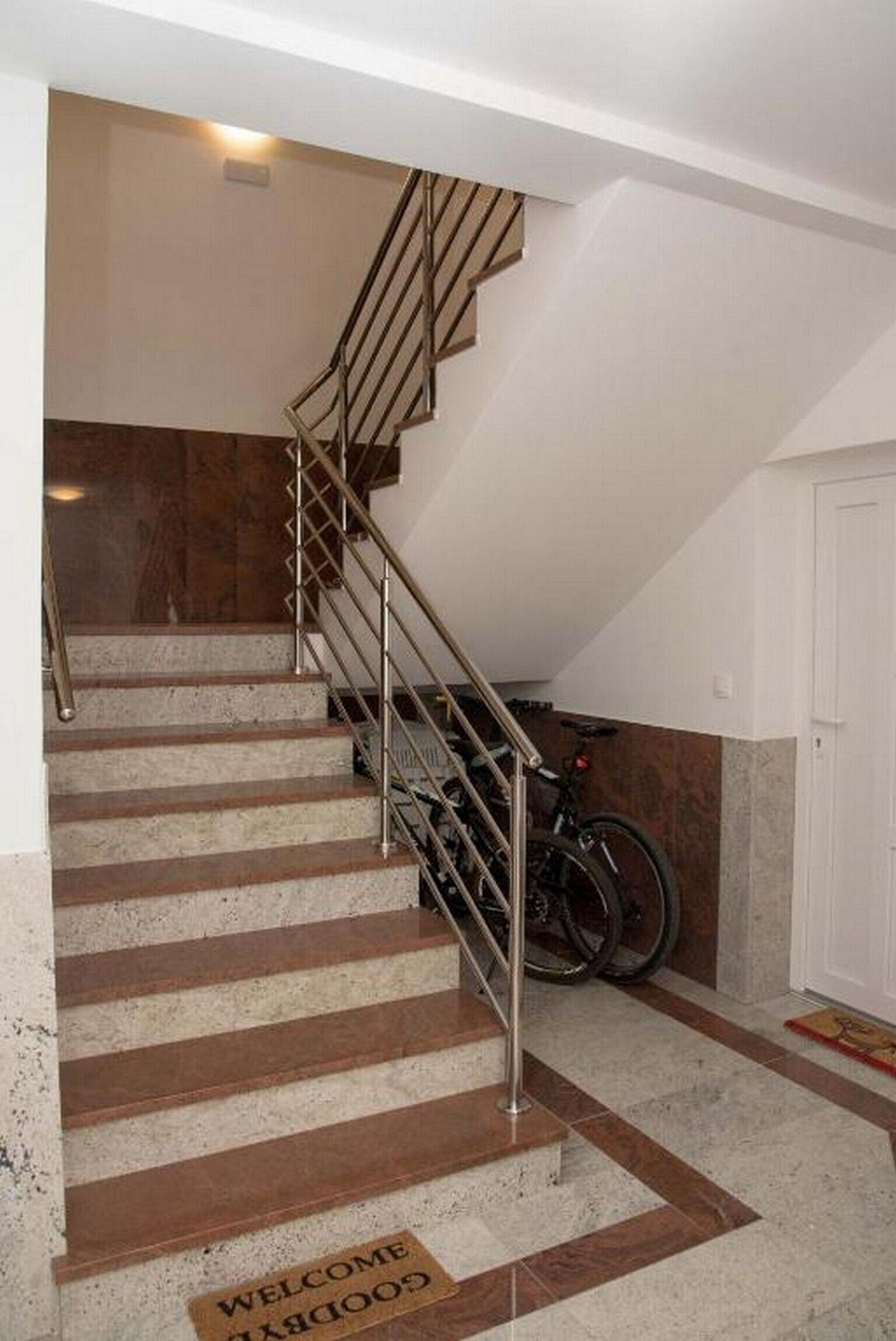 A staircase with metal railings leading to a landing, a door, and a bicycle parked against the wall.