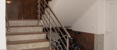 A staircase with metal railings leading to a landing, a door, and a bicycle parked against the wall.