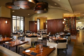 A spacious restaurant with multiple dining tables and chairs, wooden paneling, and pendant lighting. - Orlando | Resort Escape | Pool & Theme Parks Nearby (Orlando)