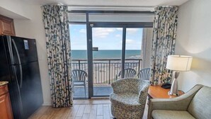 Une chambre avec vue sur la plage, comprenant un canapé, un fauteuil, une table et un réfrigérateur.