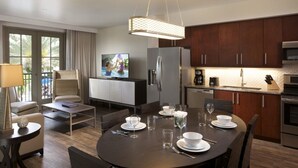 Une cuisine moderne avec des meubles en bois foncé, des appareils en acier inoxydable et un coin repas doté d’une table ronde prévue pour quatre personnes.