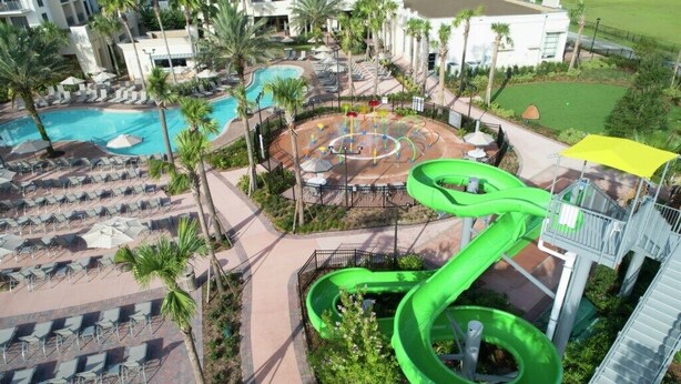 Un complexe hôtelier doté d’une grande piscine, d’un toboggan aquatique et de chaises longues.