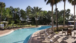 A swimming pool with lounge chairs and palm trees.