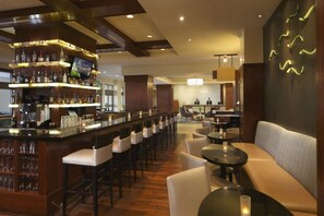A bar area with multiple seating options, including bar stools and round tables, and a television mounted on the wall. - Orlando | Park Escape | Pool & Attractions | 2BR Plus (Orlando)