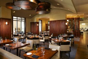 A spacious restaurant with multiple dining tables and chairs, wooden paneling, and pendant lighting. - Orlando | Park Escape | Pool & Attractions | 2BR Plus (Orlando)