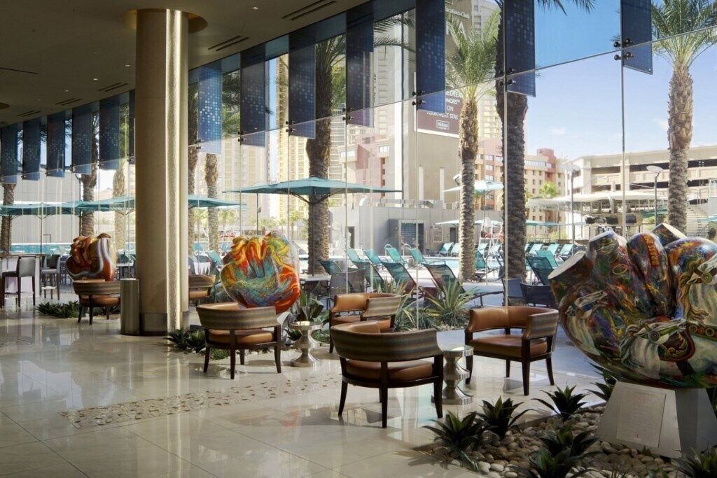 A spacious lobby with modern furniture, large windows, and decorative art pieces.