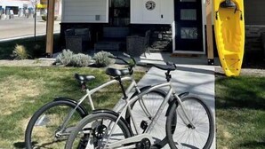 A two-story white building with a covered porch, a bicycle, and a yellow kayak. - Local Host: 3BR 2.5BA by BSU DT GreenBelt & Skiing (Boise)