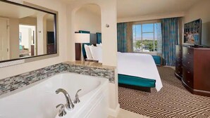 A hotel room with a large bathtub, a bed with a green bedspread, a dresser, and a view of the outdoors. - Paradise, a Hilton Grand Vacations Club - 1 Bedroom - EP (Las Vegas)