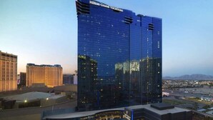 Un moderno hotel de altura con fachada de vidrio, llamado Hilton Grand Vacations, con un letrero llamativo en la parte superior.