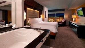 Habitación de hotel con una bañera grande, dos camas, un escritorio y un televisor.
