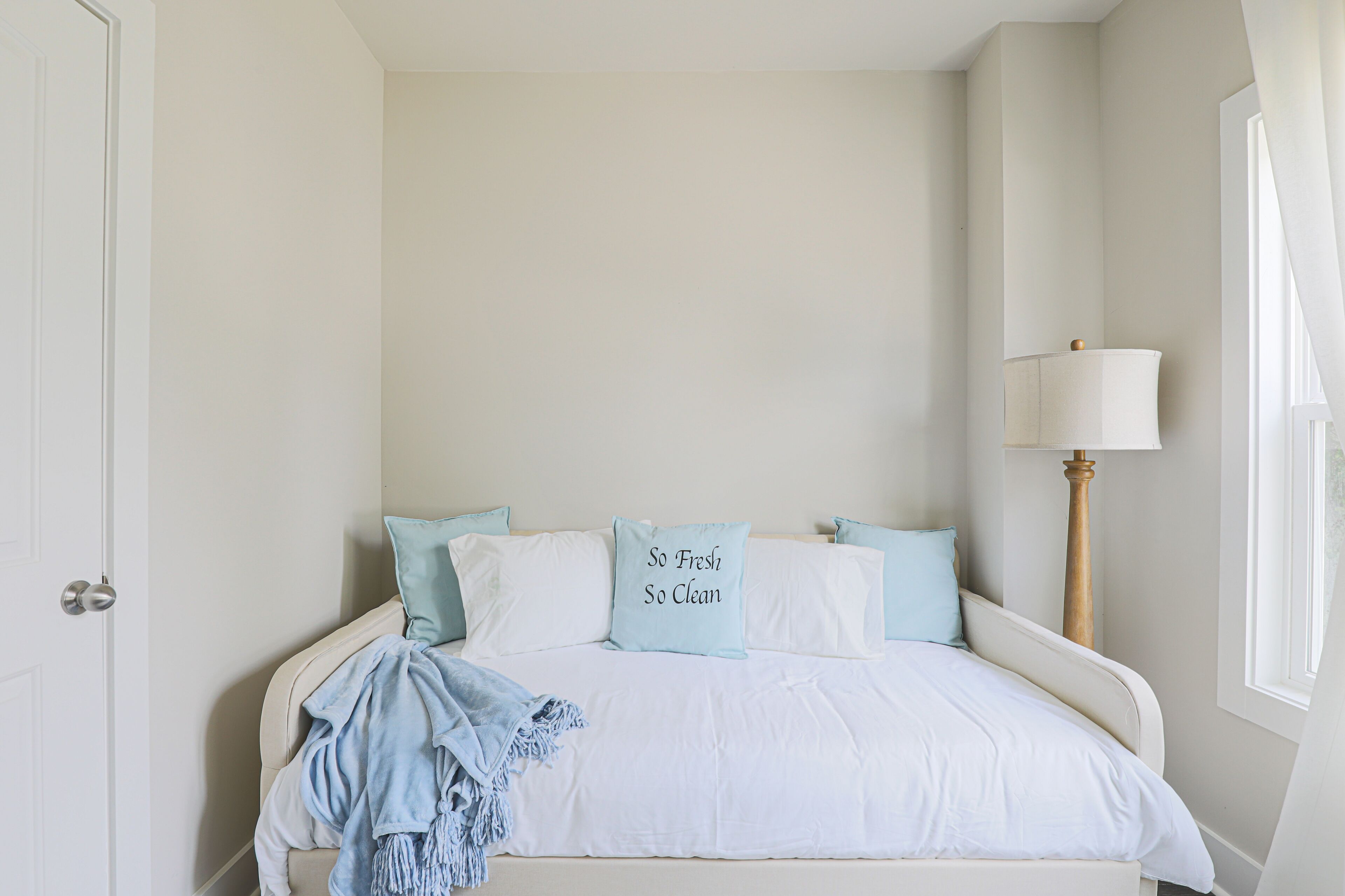 A bedroom with a bed, pillows, a lamp, and a window.