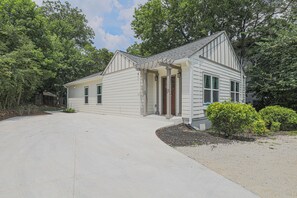 A single-story house with a covered porch, a driveway, and a small garden area.
