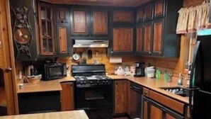 A kitchen with wooden cabinets, a stove, a microwave, and a refrigerator.