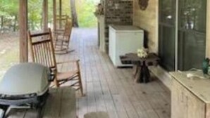 A covered porch with wooden flooring, a bench, and a table.