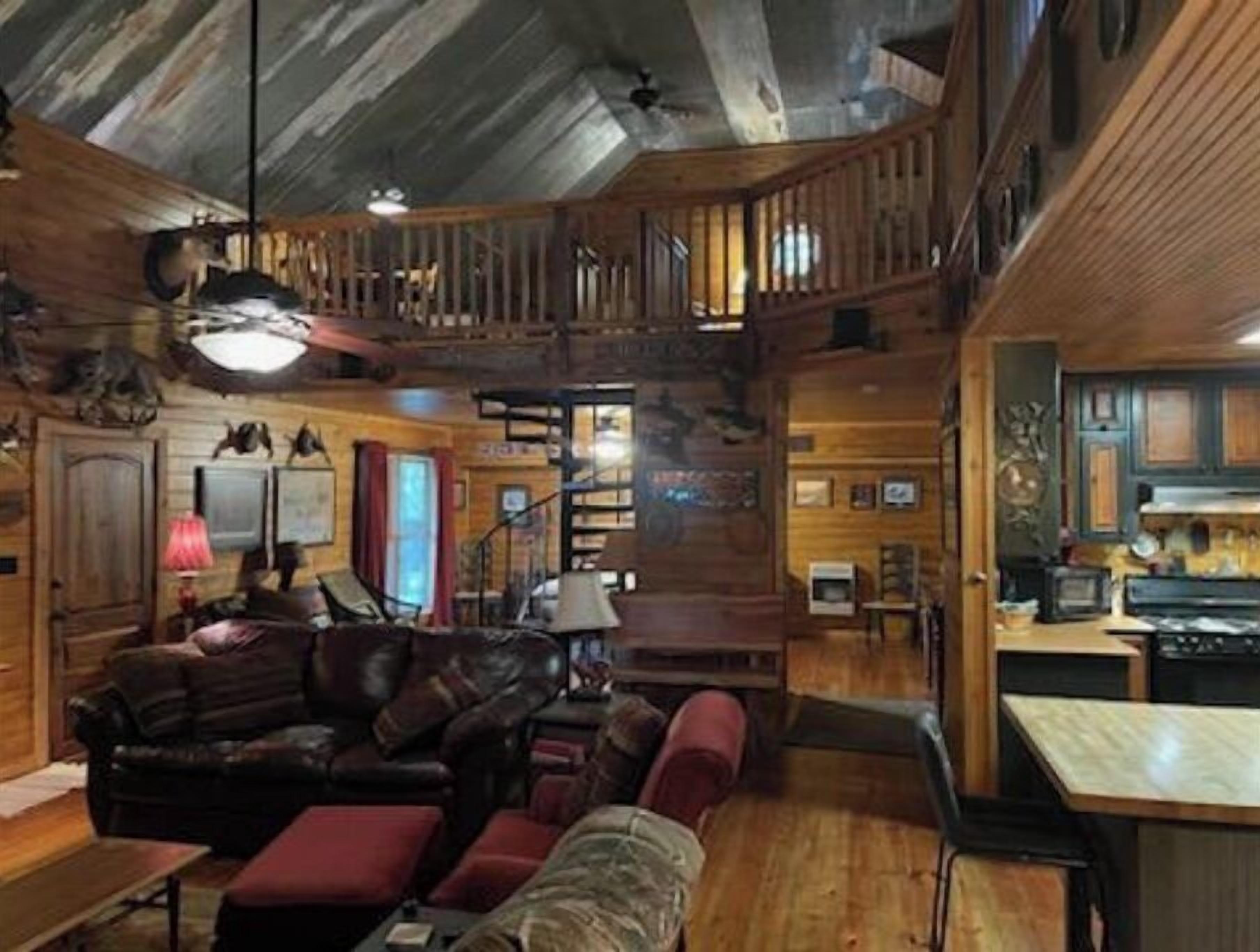 A cozy cabin interior with a living room, a staircase, and a kitchen area.