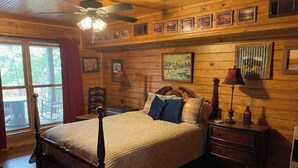 A wooden-paneled bedroom with a four-poster bed, a ceiling fan, and a large window with curtains.