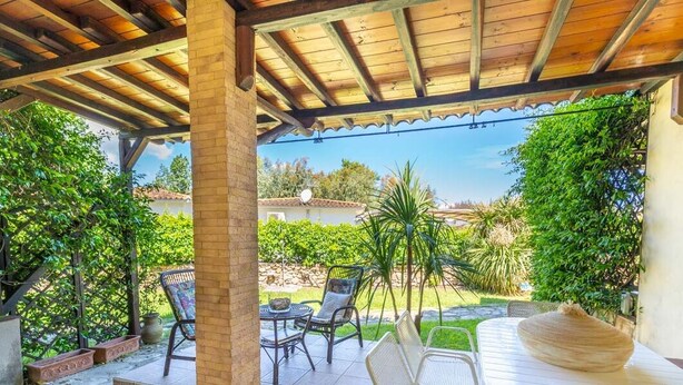 Un espace extérieur aménagé en terrasse, avec une pergola en bois, une table et des chaises, ainsi qu’un grand panier en osier.