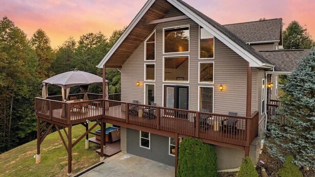 A two-story house with a deck, large windows, and a covered patio. - Relaxing Hideaway, Sleeps 11・Theater・Games・Hot Tub (Sevierville)