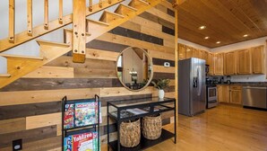 A wooden staircase with a modern kitchen area featuring wooden cabinets, a stainless steel refrigerator, and a black console table with wicker baskets. - Relaxing Hideaway, Sleeps 11・Theater・Games・Hot Tub (Sevierville)