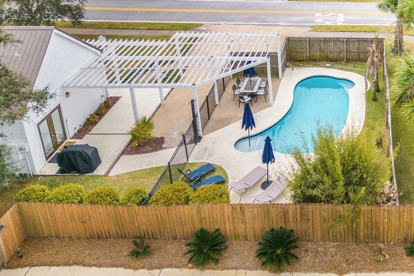 A residential backyard with a swimming pool, patio furniture, and a pergola.