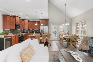 A modern kitchen with wooden cabinets, stainless steel appliances, and a dining area with wicker chairs and a wooden table.
