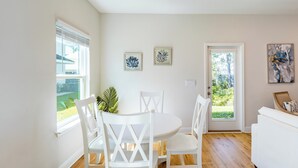 A dining area with a round table and white chairs, a potted plant, and artwork on the walls. - Santa Rosa Hideaway by Avantstay Pet Friendly 6 Mins to Beach! (Santa Rosa Beach)
