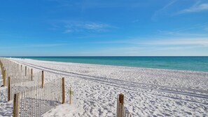 A sandy beach with a wooden fence and a clear blue sky.