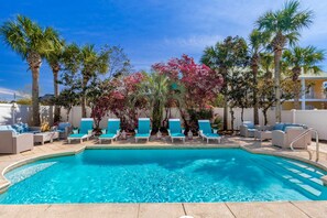 A swimming pool with lounge chairs and palm trees.