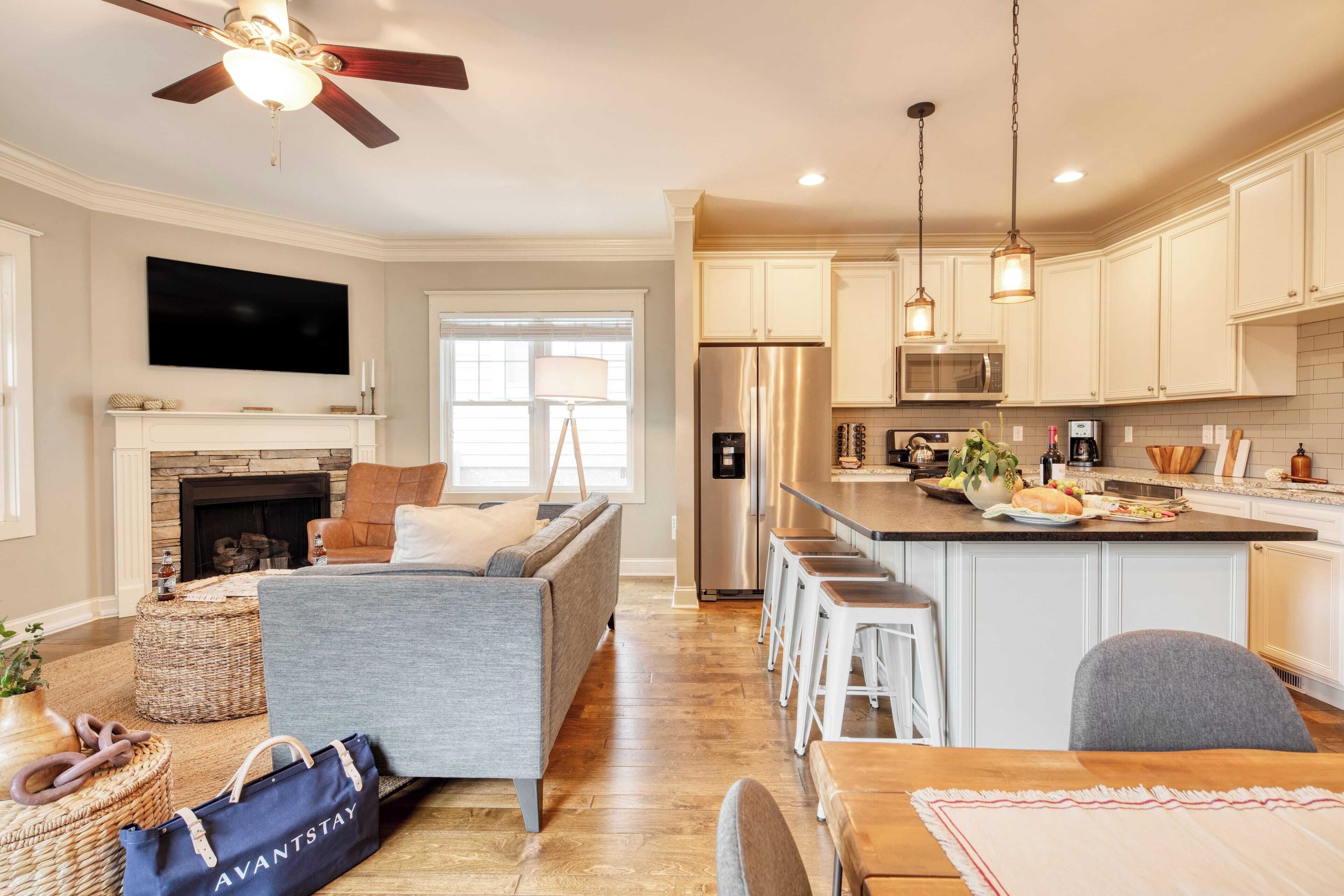 A modern kitchen with a central island, bar stools, and a dining table.