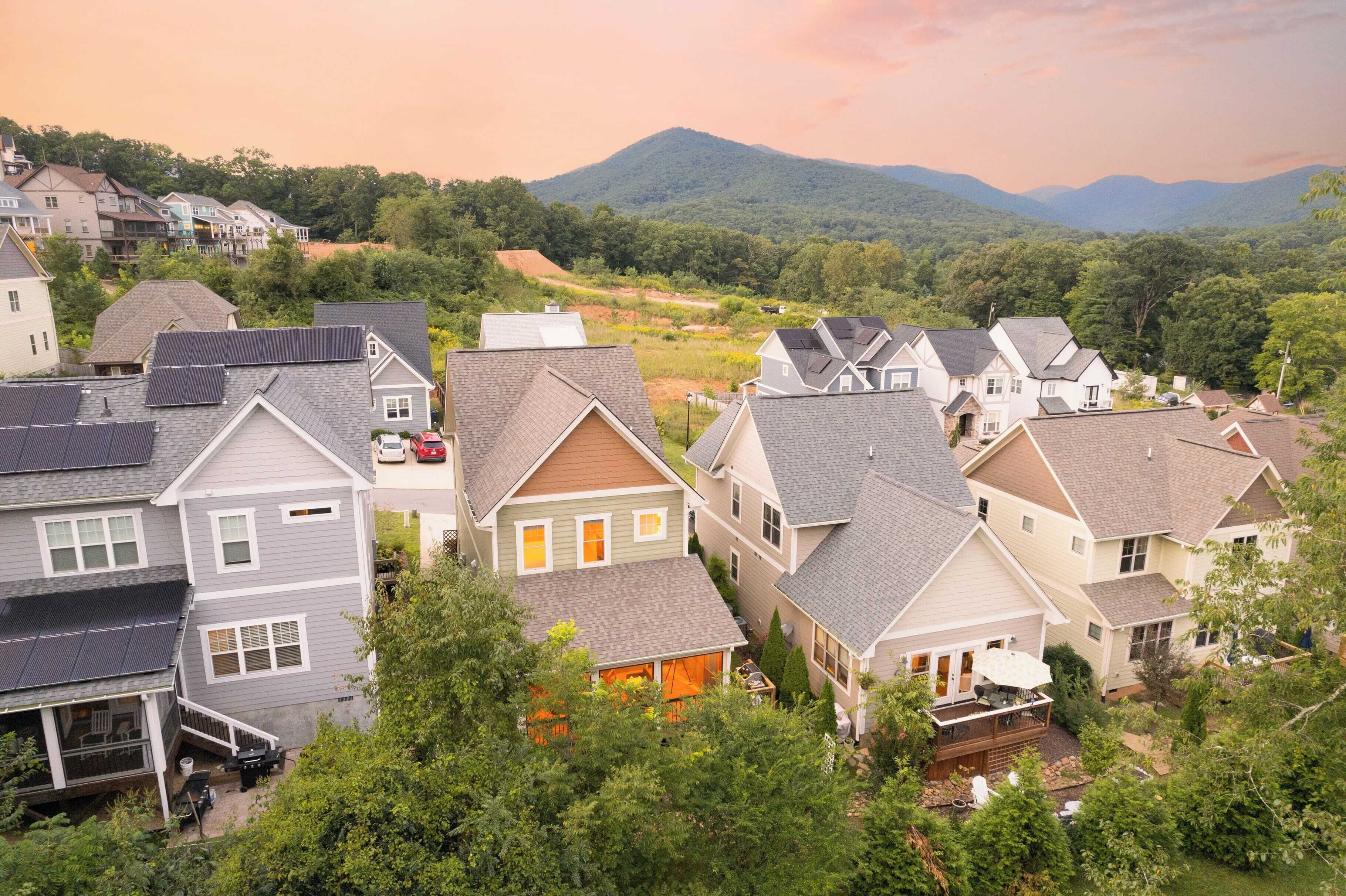 Uma área residencial com casas, uma entrada de automóveis e uma montanha ao fundo.