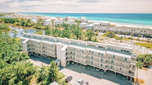 Ett hotell med flera våningar, balkonger, en parkeringsplats och utsikt över stranden.