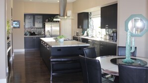 A modern kitchen with a central island, black chairs, and a dining table. - RANCHO MIRAGE - VICTORIA FALLS ENTERTAINING 4 BD - HUGE POOL & SPA & GRASS YARD! (Rancho Mirage)
