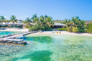 A coastal resort with clear turquoise waters, a dock with boats, and palm trees.