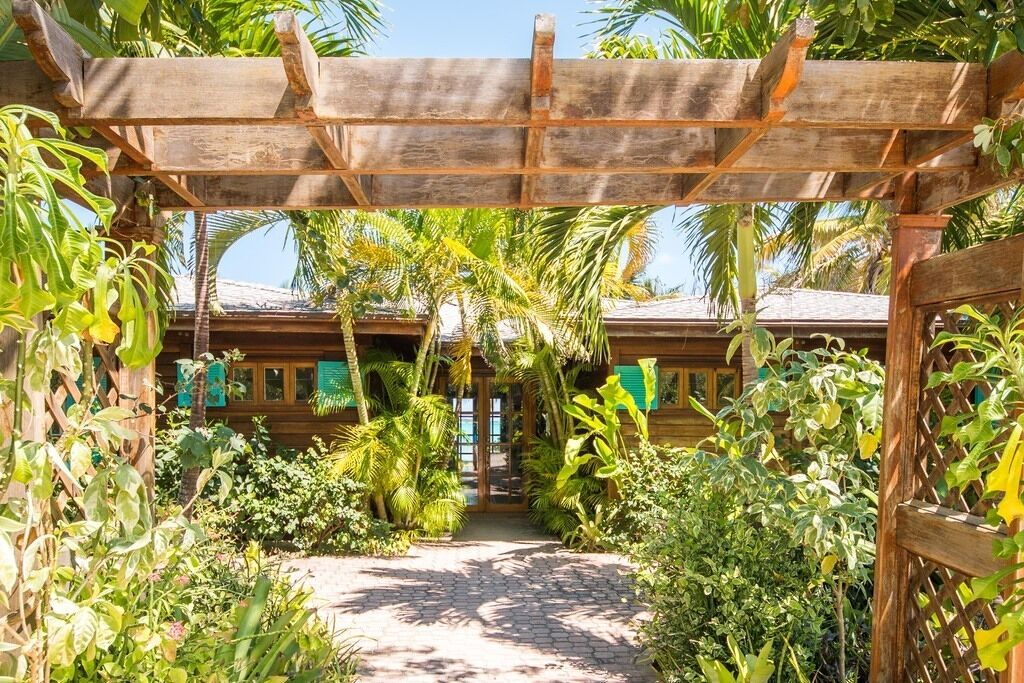 Een houten pergola met een pad dat naar een houten gebouw leidt.