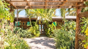 A wooden pergola structure with a pathway leading to a wooden building.