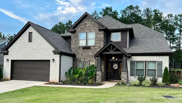A two-story house with a stone facade, a garage, and a well-maintained lawn. - LUX House! HOT TUB! 4 min to campus. Golf lot (Auburn)