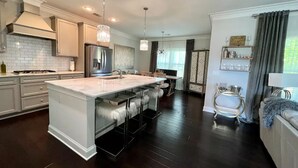 A modern kitchen with a central island, stainless steel appliances, and pendant lighting. - LUX House! HOT TUB! 4 min to campus. Golf lot (Auburn)