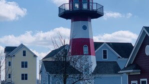 A lighthouse with a red and white striped tower, surrounded by residential houses with various architectural styles. - Perfect for Fall Getaway - Firepit : Walk to Water (Buckeye Lake)