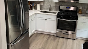 A modern kitchen with white cabinets, stainless steel appliances, and a wooden floor. - Perfect for Fall Getaway - Firepit : Walk to Water (Buckeye Lake)