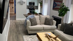 A modern living room with a sofa, coffee table, and a view into the kitchen. - Perfect for Fall Getaway - Firepit : Walk to Water (Buckeye Lake)