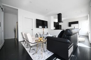 Un salon moderne avec un canapé noir, un fauteuil blanc et une table basse agrémentée d’un élément décoratif central.