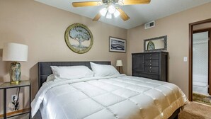 A bedroom with a bed, a ceiling fan, a nightstand, a dresser, and a door leading to a balcony. - Comfy 1 bed/1 bath - 6 blocks from Mayo (Rochester)