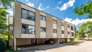 A multi-story building with a flat roof, large windows, and a parking area with a car. - Modern, Rustic 2 Bed/1 bath 6 blocks from Mayo (Rochester)