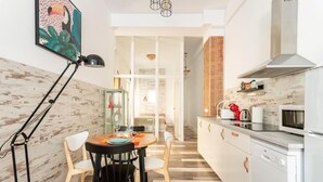 A modern kitchen with white cabinets, a microwave, and a coffee maker. There is a dining area with a table and chairs. - San Fernando Garden (Alicante (Alacant))