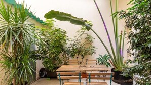 A wooden table with benches in a garden area with various potted plants. - San Fernando Garden (Alicante (Alacant))