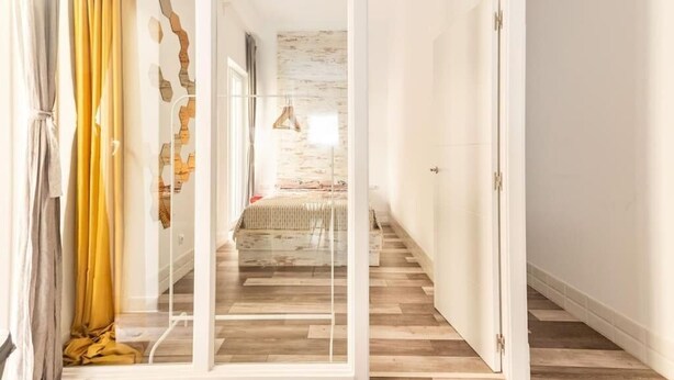 A modern interior with a wooden floor, a bed with a white headboard, and a staircase leading to another room. - San Fernando Garden (Alicante (Alacant))