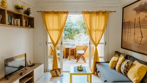 Ein Wohnzimmer mit einer Couch, einem Fernseher und einem Essbereich mit Stühlen und einem Tisch.
