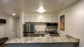 A kitchen with white cabinets, stainless steel appliances, granite countertops, and a bar area with stools. - New Listing -- Modern on the Mtn -- Steps to Ski! (Steamboat Springs)
