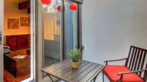 A wooden table with a potted plant and a red cushion, a sliding glass door, and a red lantern hanging above. - New Listing -- Modern on the Mtn -- Steps to Ski! (Steamboat Springs)