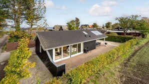Une maison moderne dotée d’un grand patio, d’un coin repas et offrant une vue sur le quartier environnant.